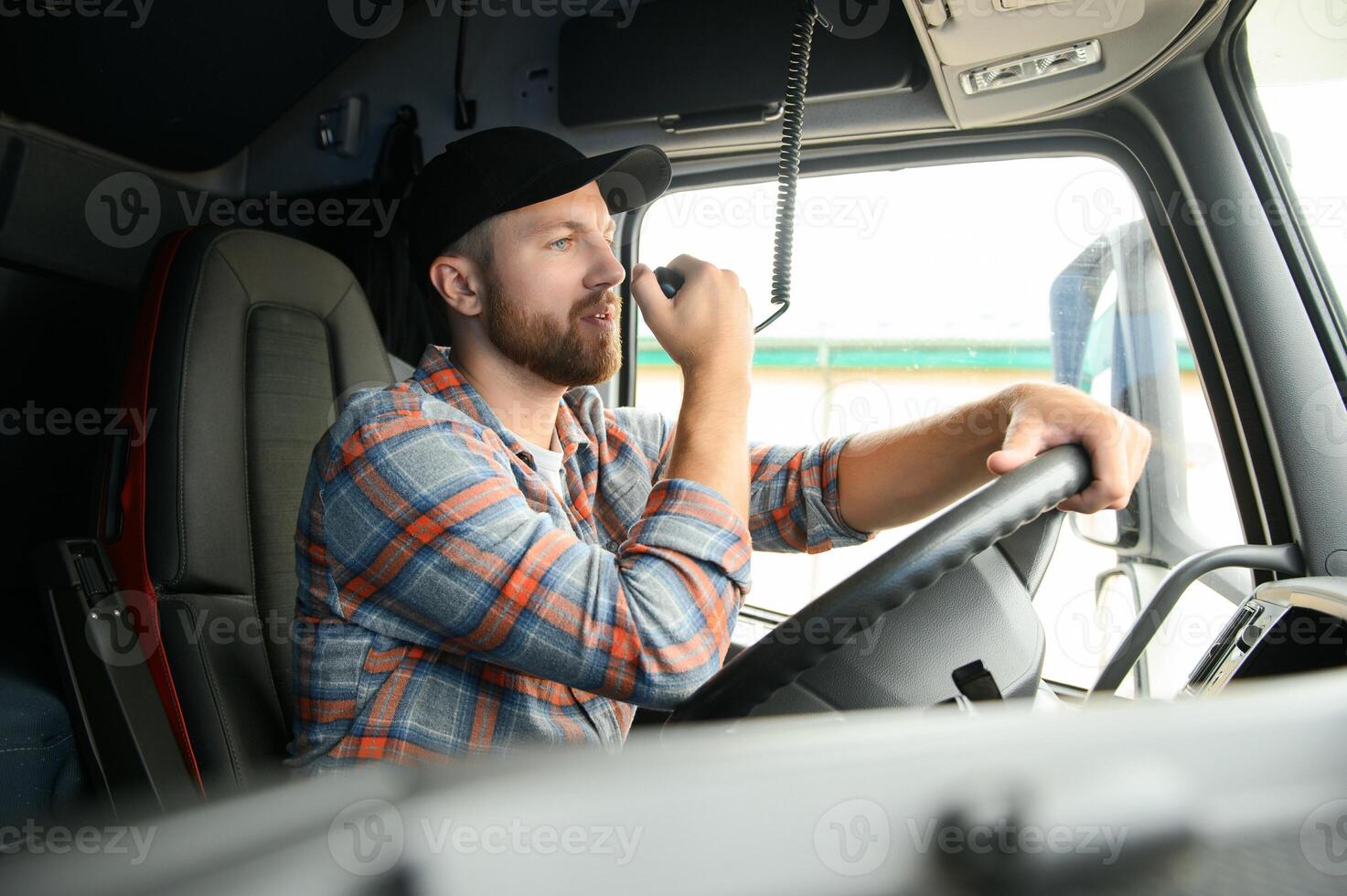 Man trucker driving in a cabin of his truck and talking on radio transmitter. photo