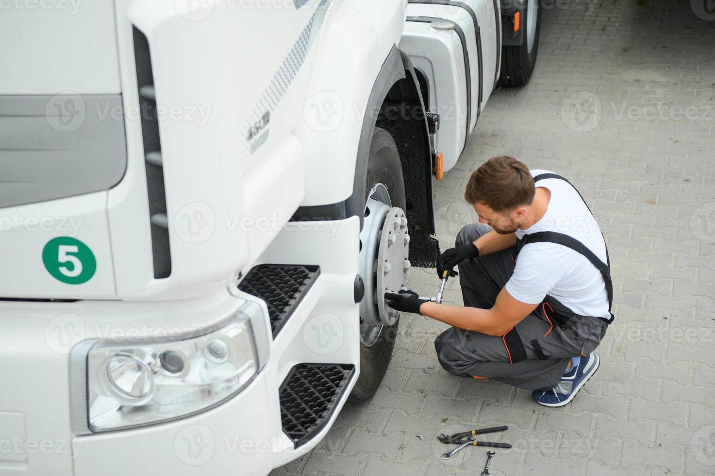 Semi Truck Under Maintenance. Caucasian Truck Mechanic Working to Fix the Tractor. photo