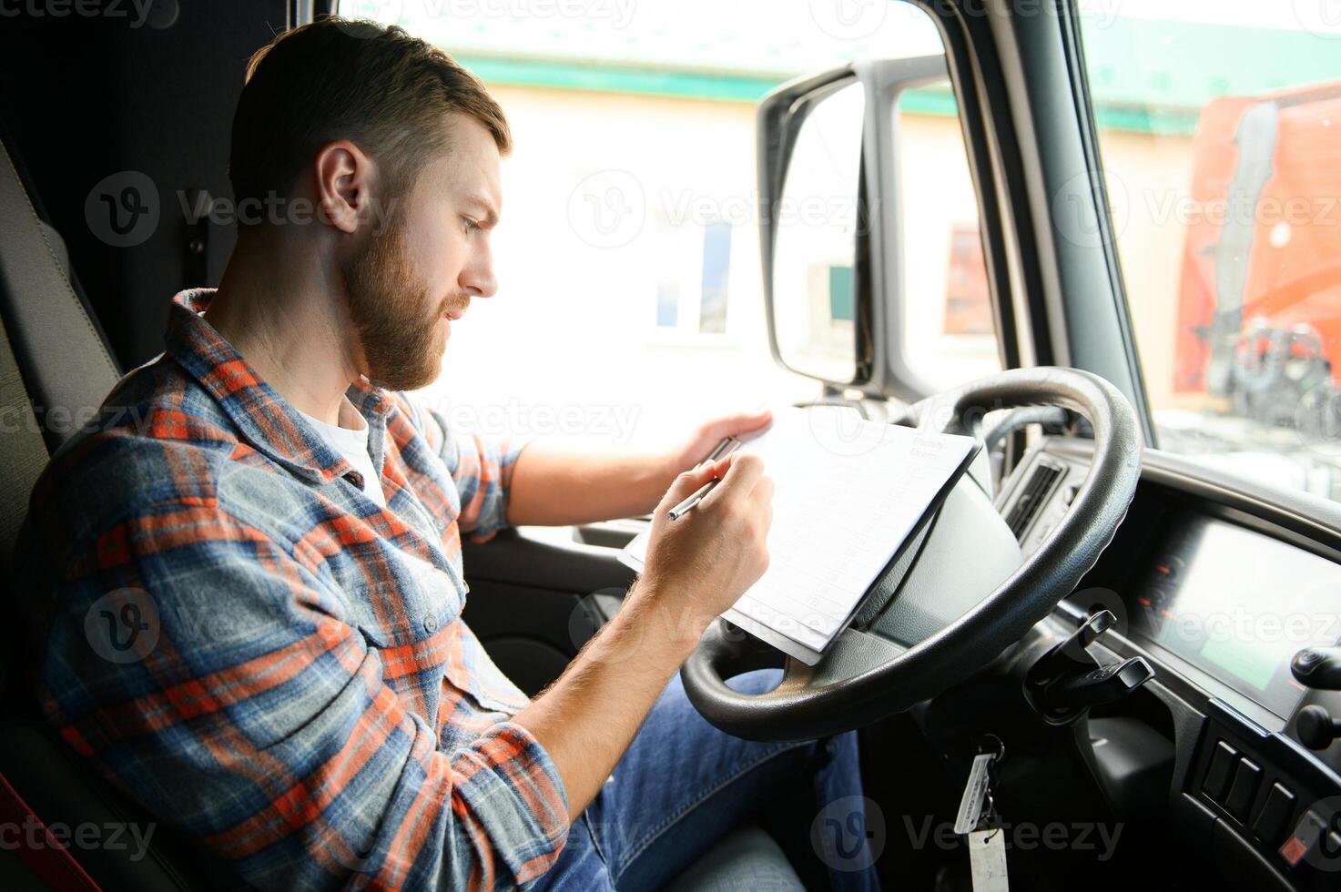 forwarder driver sits behind the wheel of a car and examines waybills documentation for the cargo. photo