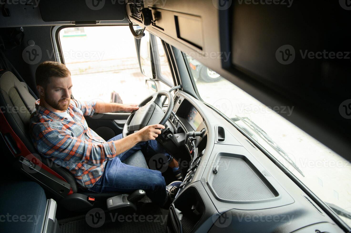 Side view of professional driver behind the wheel in truck's cabin. photo