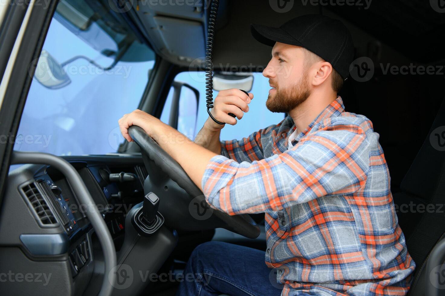 Man trucker driving in a cabin of his truck and talking on radio transmitter. photo