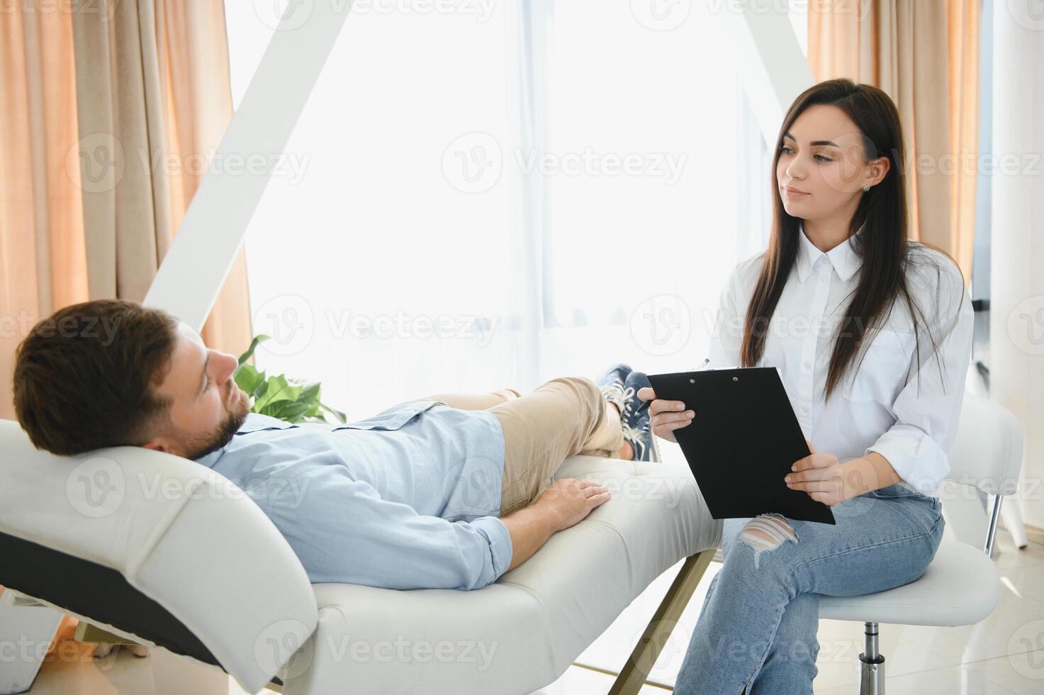 Depressed man speaking to a therapist while she is taking notes photo