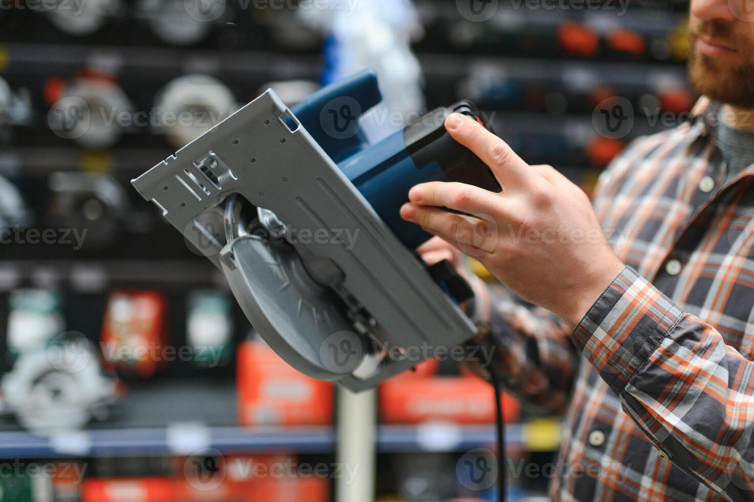 A man in a hardware store chooses a new orbital sander photo
