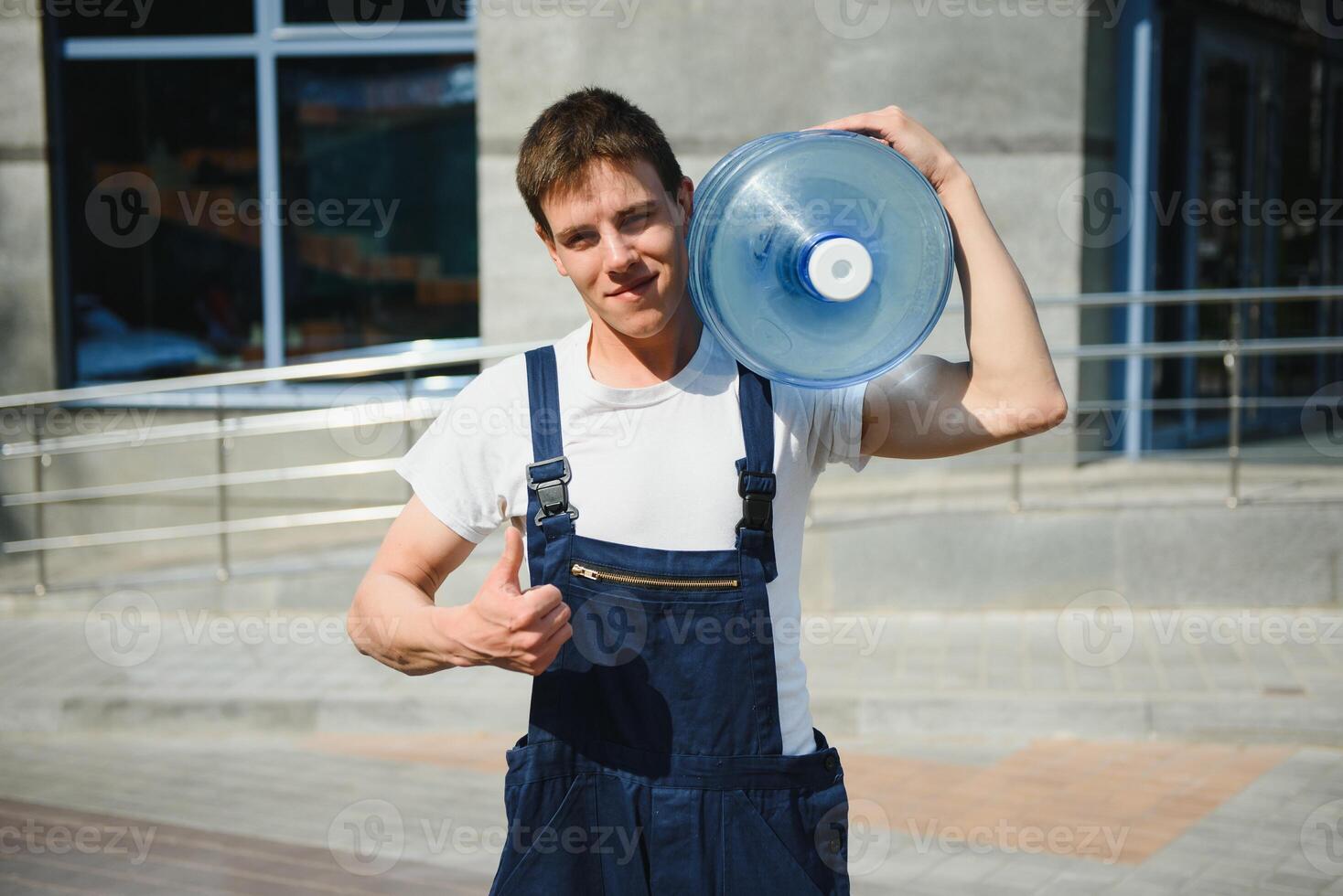 Smiling delivery man carrying water bottle on shoulder photo