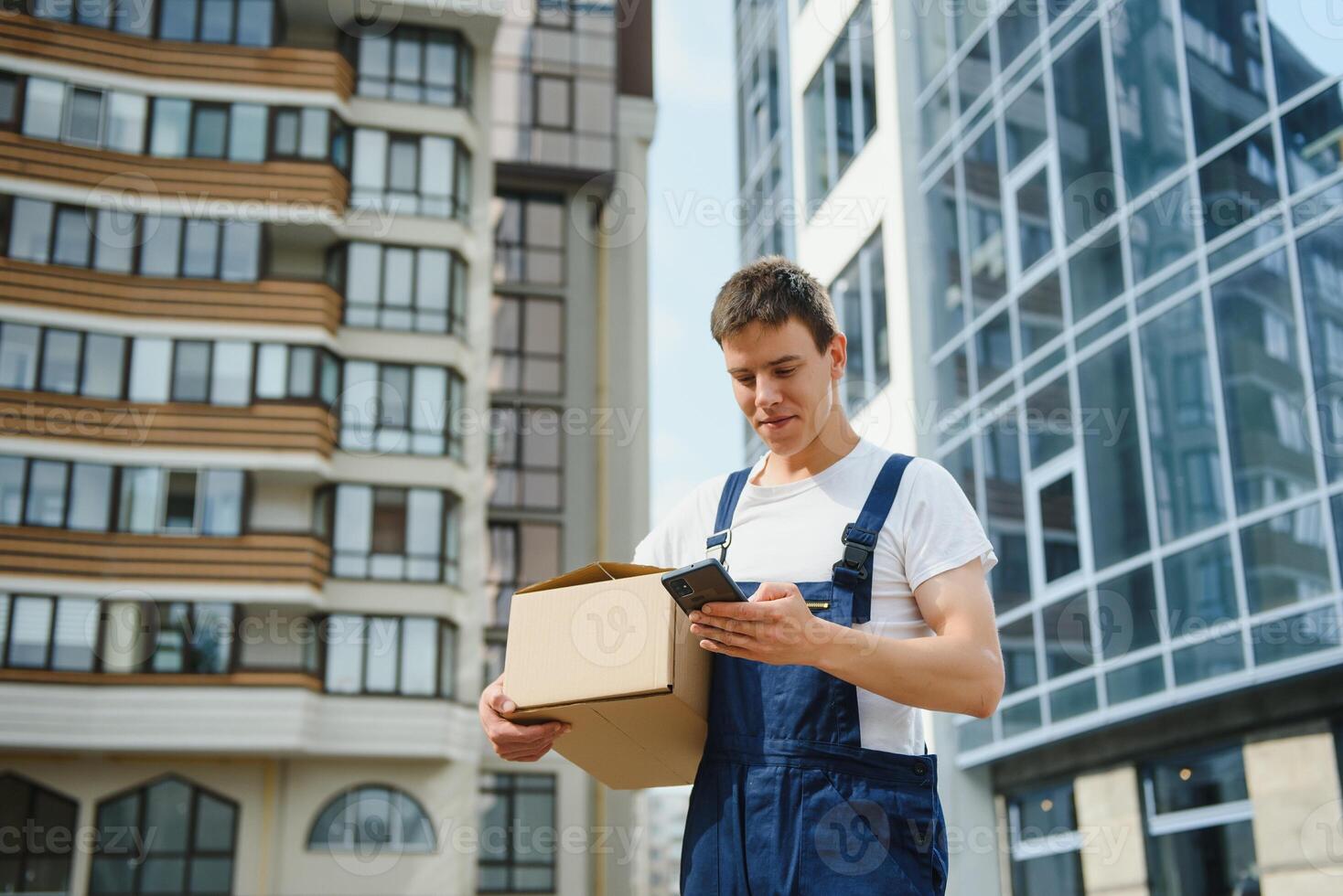 Young male courier with parcels near delivery service car photo
