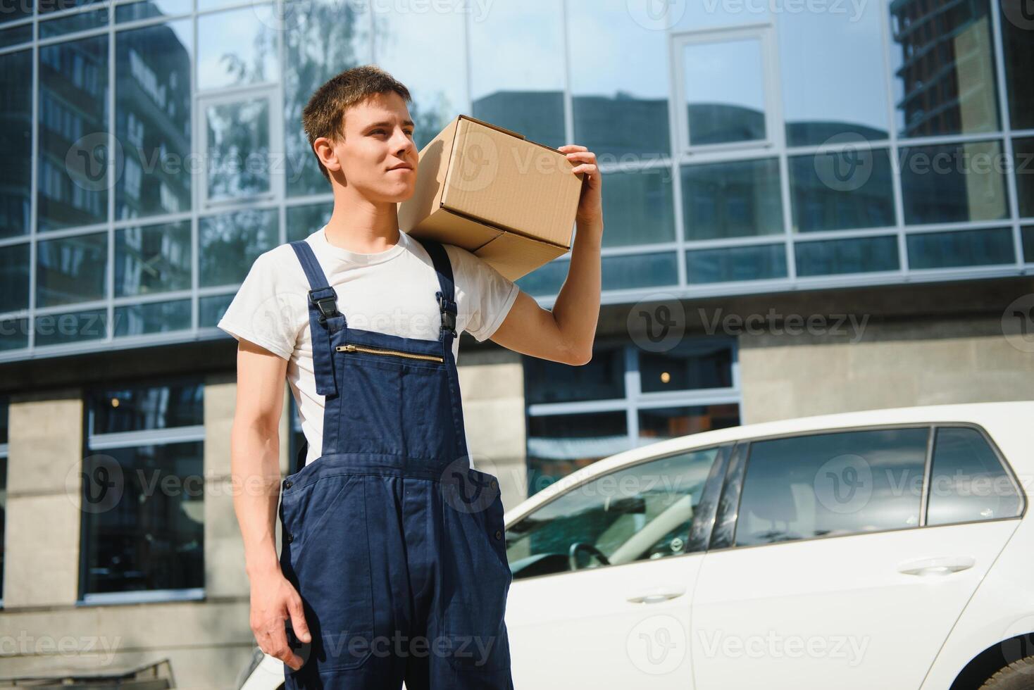 Smiling delivery man standing in front of his car photo