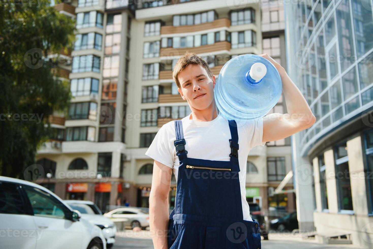 Smiling delivery man carrying water bottle on shoulder photo