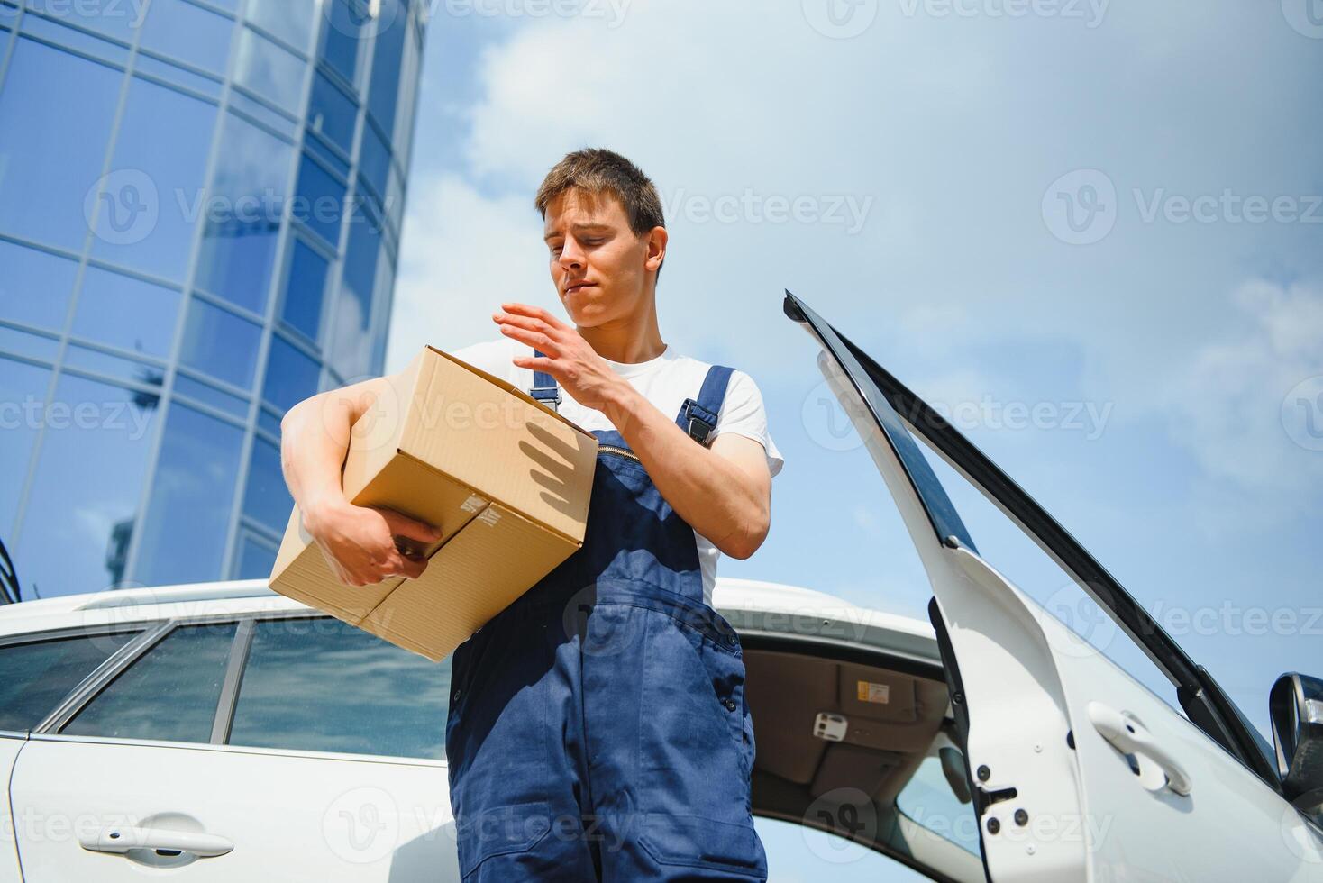 Smiling delivery man standing in front of his car photo