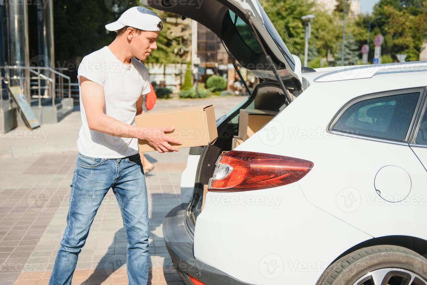Smiling delivery man standing in front of his car photo