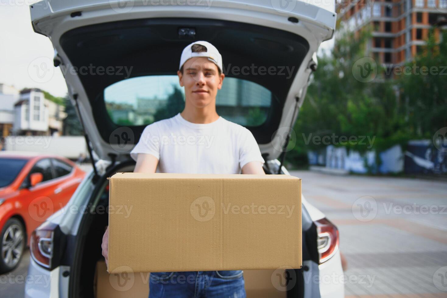Smiling delivery man holding a paper box photo