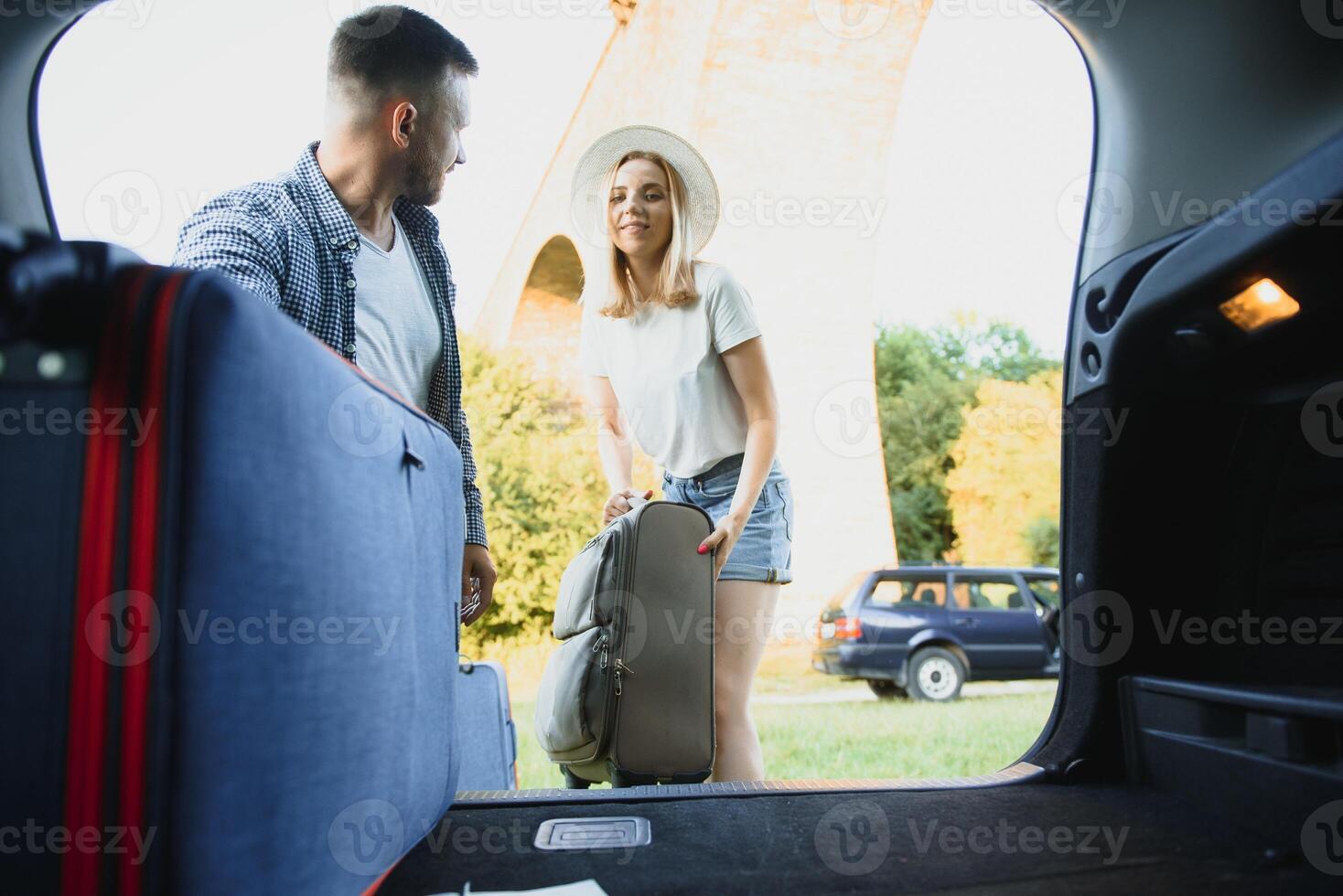 young happy couple getting ready to go on holiday vacation. put suitcases in to the car trunk photo
