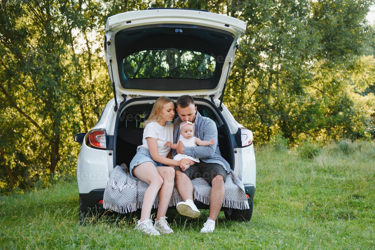 Family with kid sitting in car trunk photo
