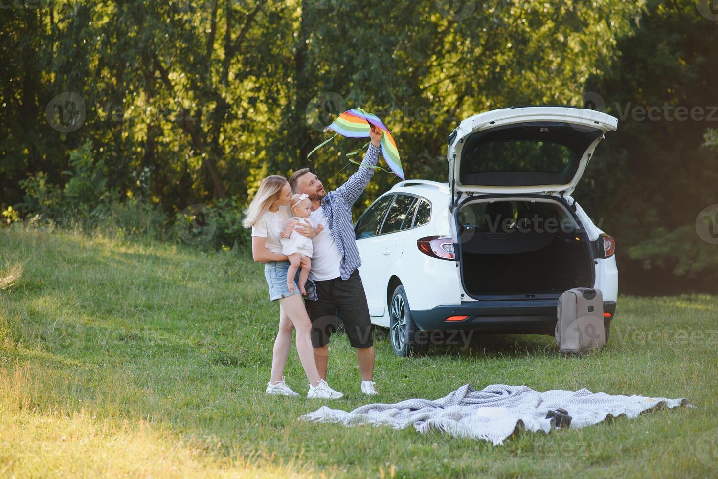 Happy family near car trunk on sunny day. Road trip photo