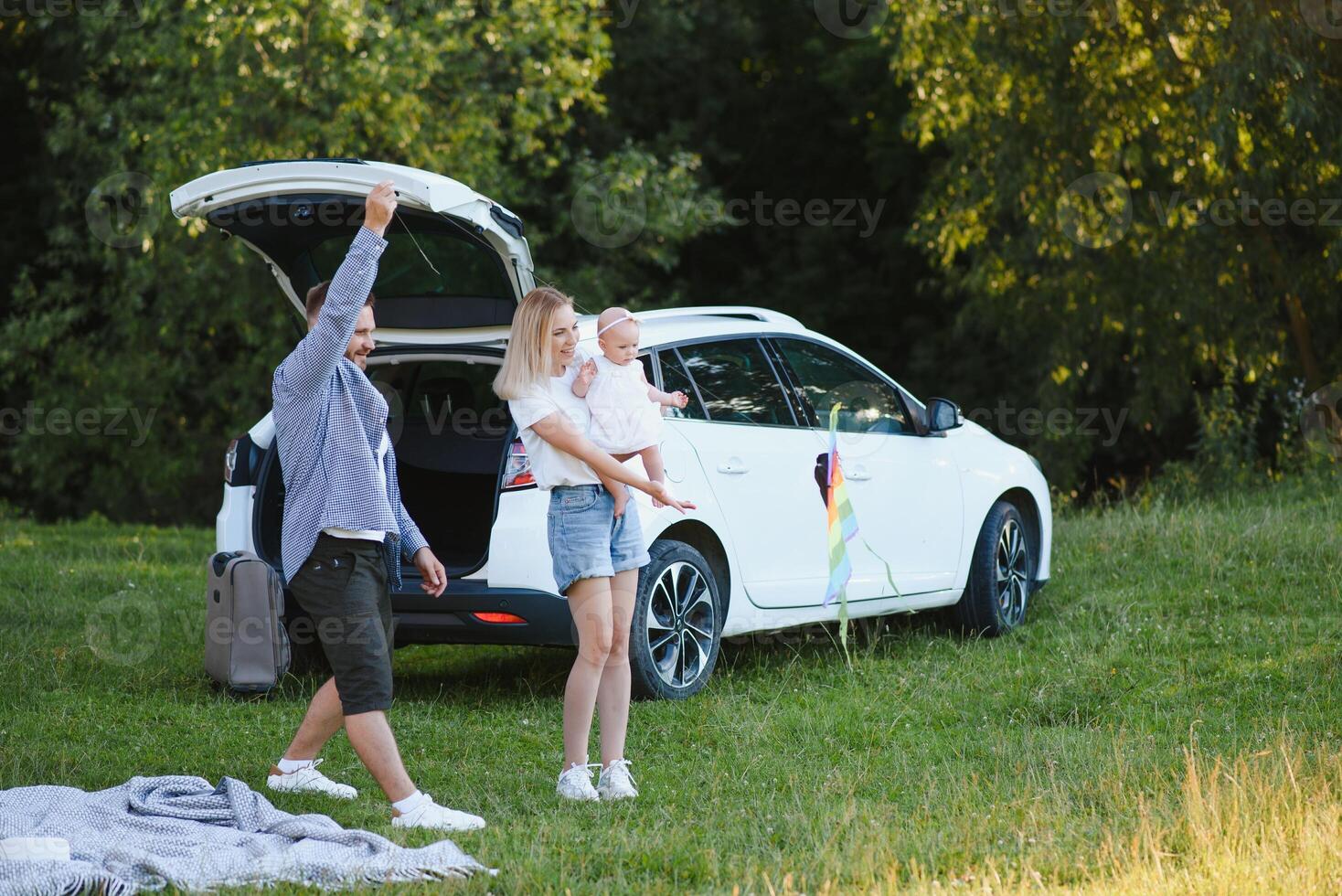 Happy family near car trunk on sunny day. Road trip photo