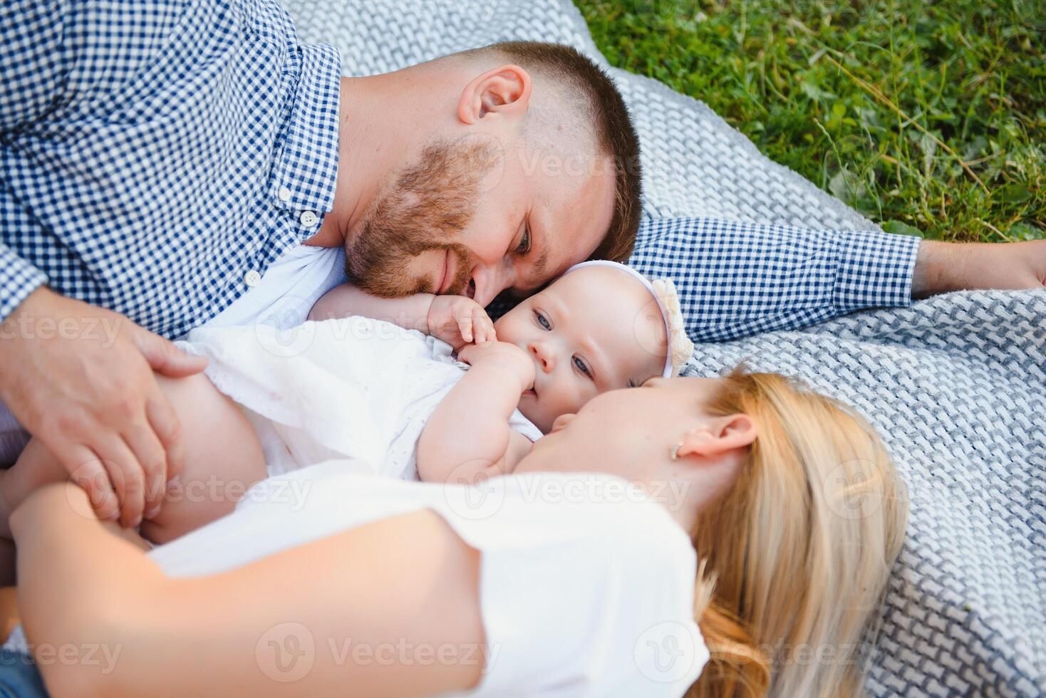 a young family lies on a blanket in a summer park photo