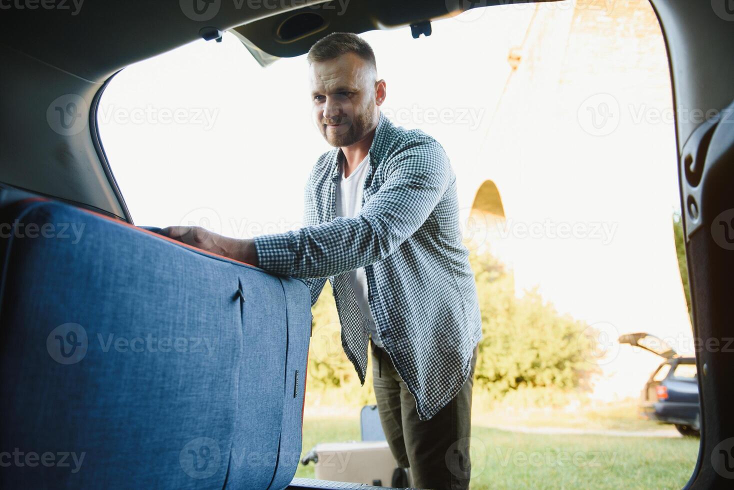 man putting bags in car trunk. ready for car travel. sunny morning photo