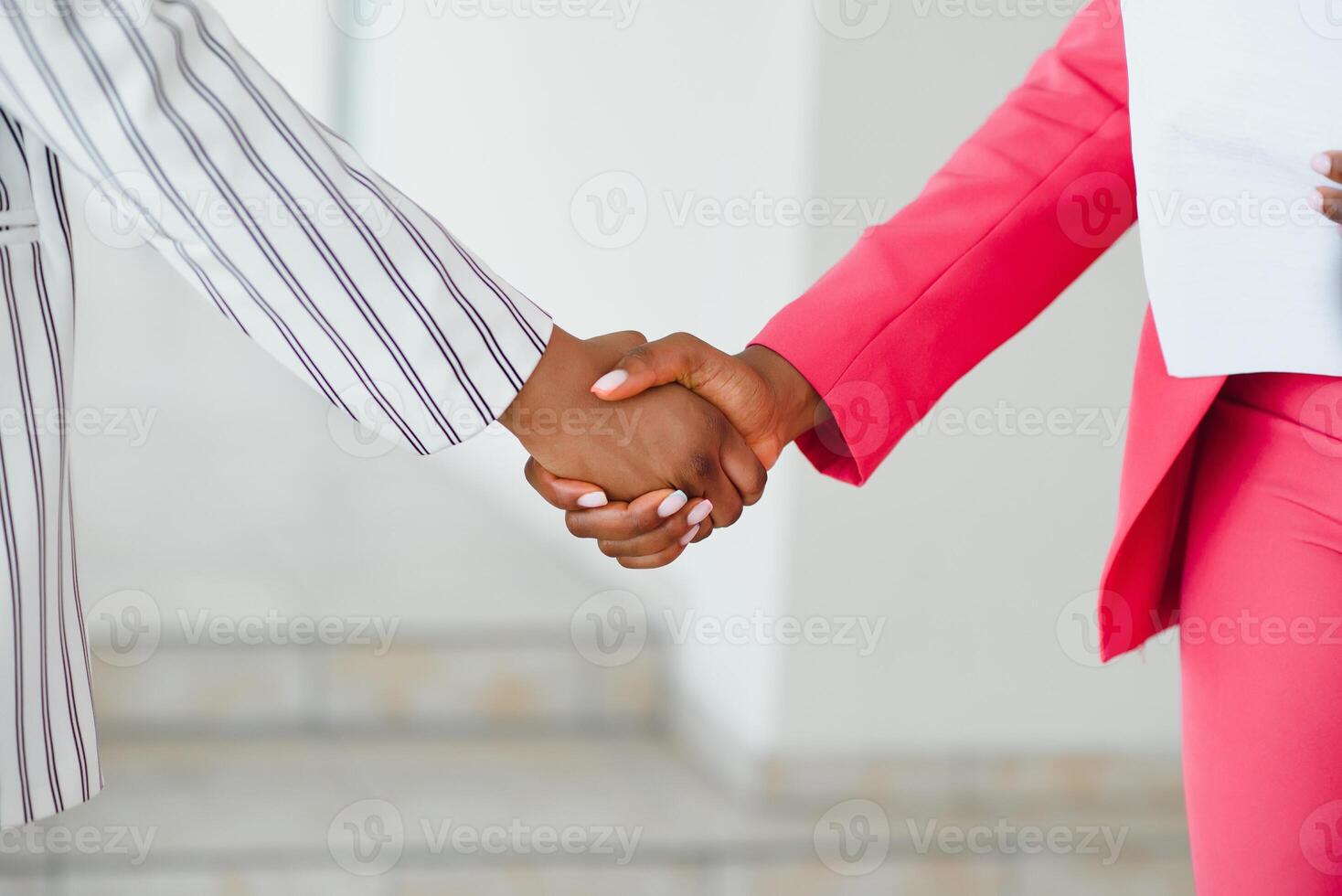 Two Businesswomen Shaking Hands In Lobby Of Modern Office photo