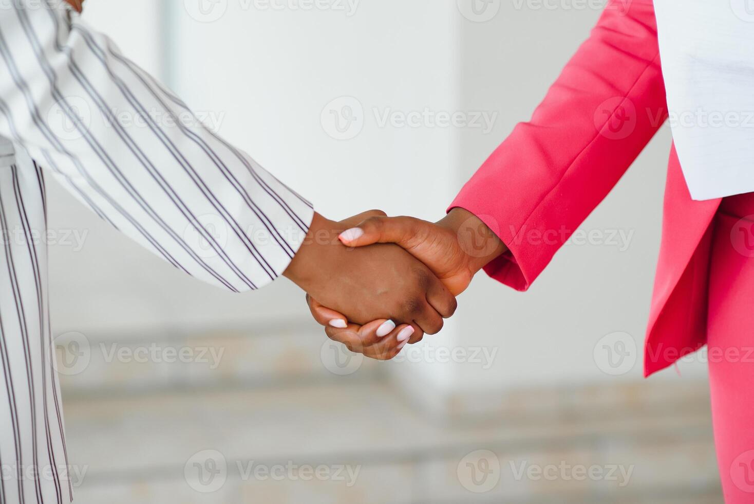 Two Businesswomen Shaking Hands In Lobby Of Modern Office photo