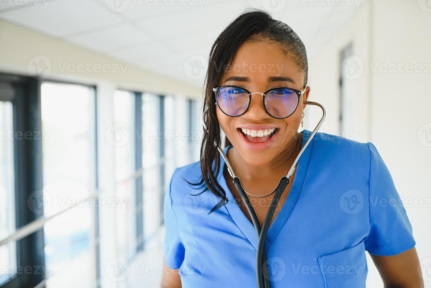 portrait of friendly, smiling confident female healthcare professional with lab coat, arms crossed holding glasses. Isolated hospital clinic background. photo