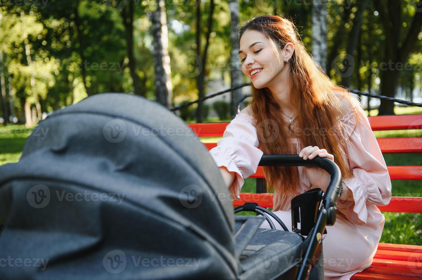 family, child and parenthood concept - happy mother walking with baby stroller in park. photo