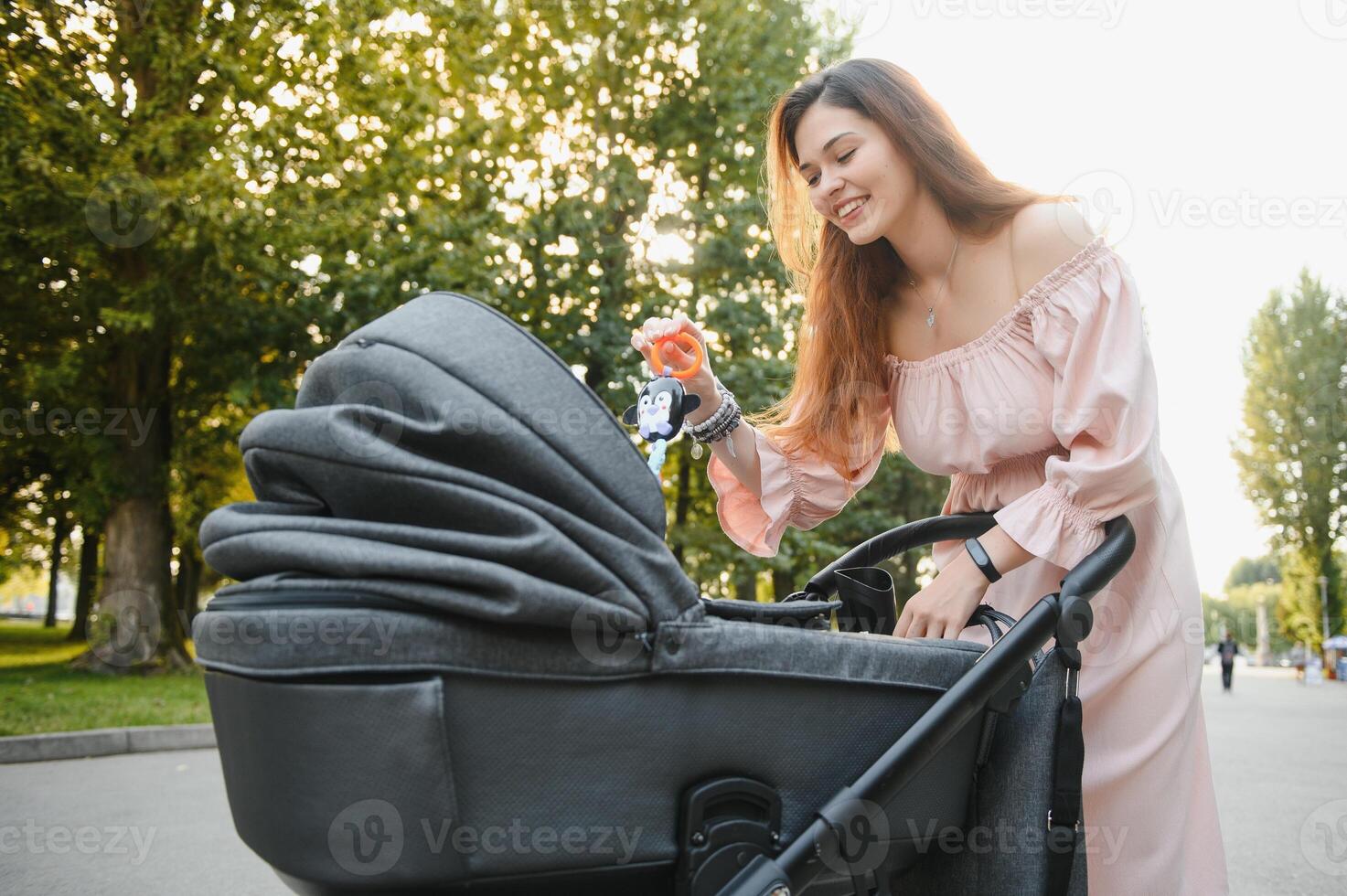 family, child and parenthood concept - happy mother walking with baby stroller in park. photo