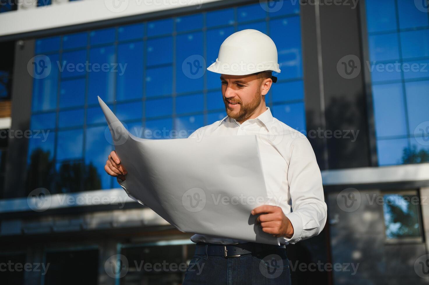 Successful engineer or architect, crane and building construction at backgrpound. Joyous businessman wearing helmet photo