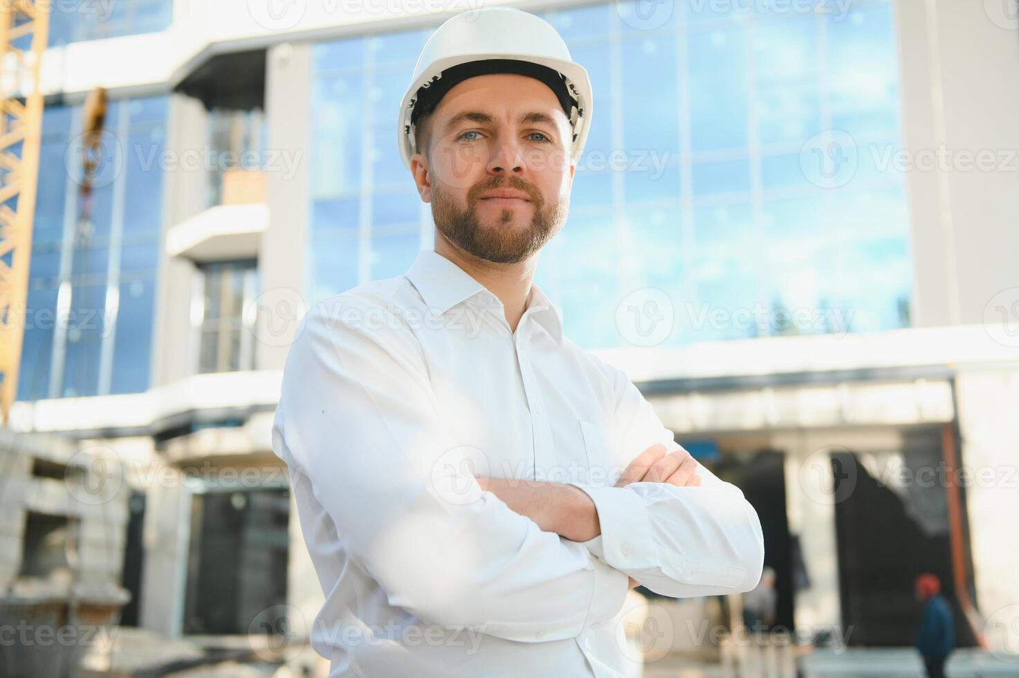 Successful engineer or architect, crane and building construction at backgrpound. Joyous businessman wearing helmet photo