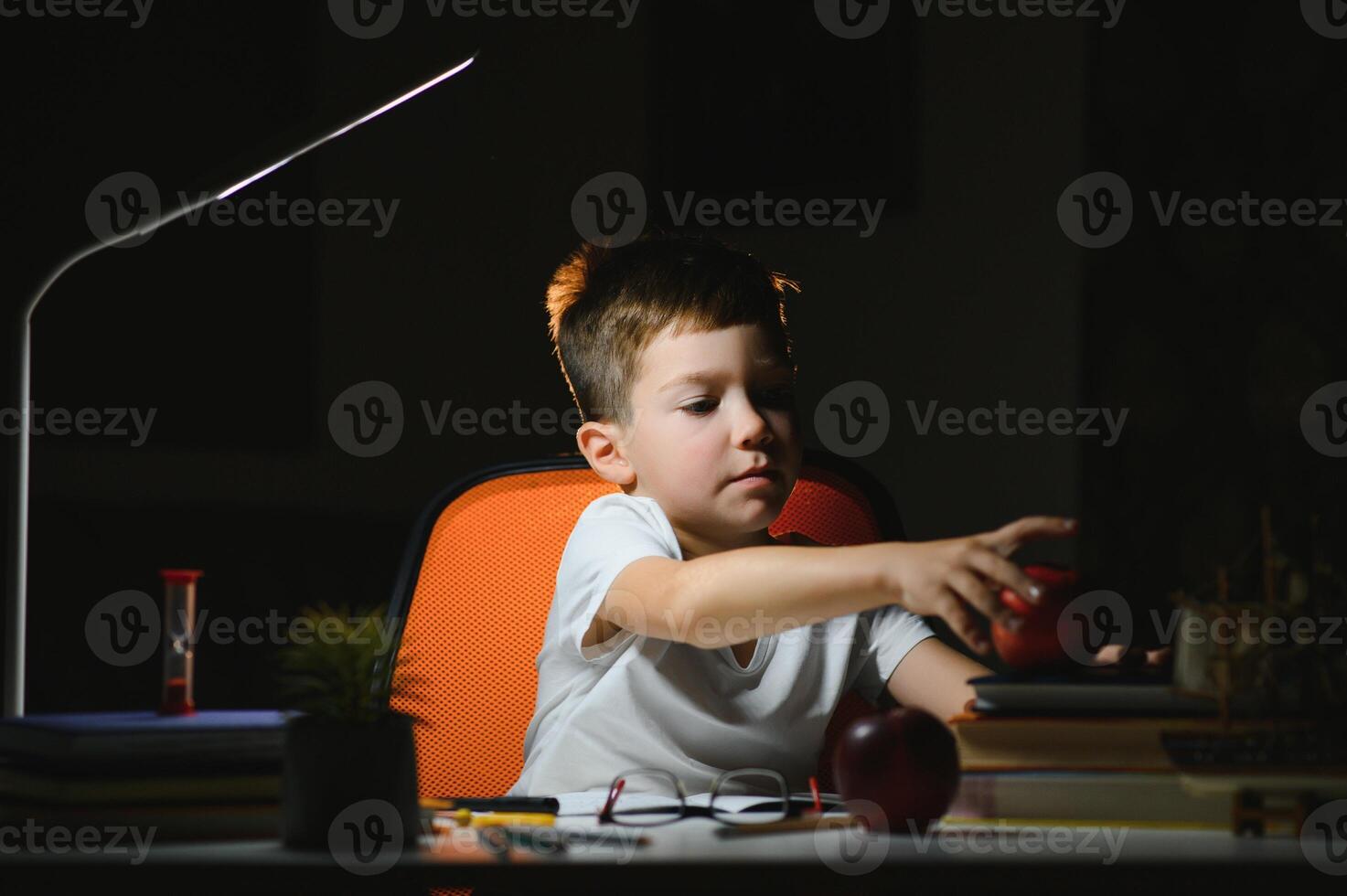 Boy learn lessons in the home setting at the table in the light of a table lamp. photo
