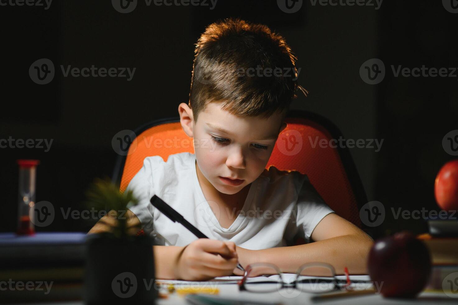 Boy learn lessons in the home setting at the table in the light of a table lamp. photo