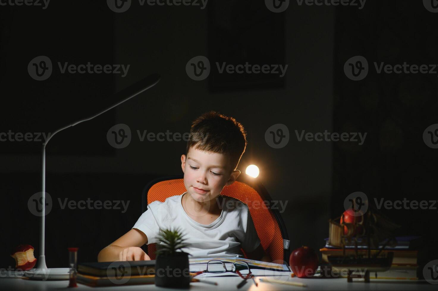 Boy learn lessons in the home setting at the table in the light of a table lamp. photo
