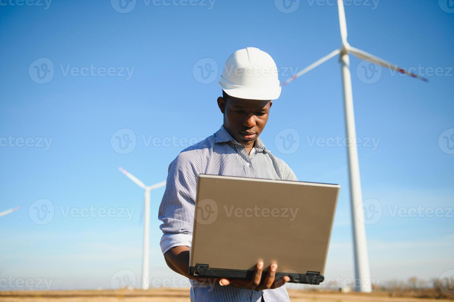 African Engineer standing and hoding laptop with wind turbine photo