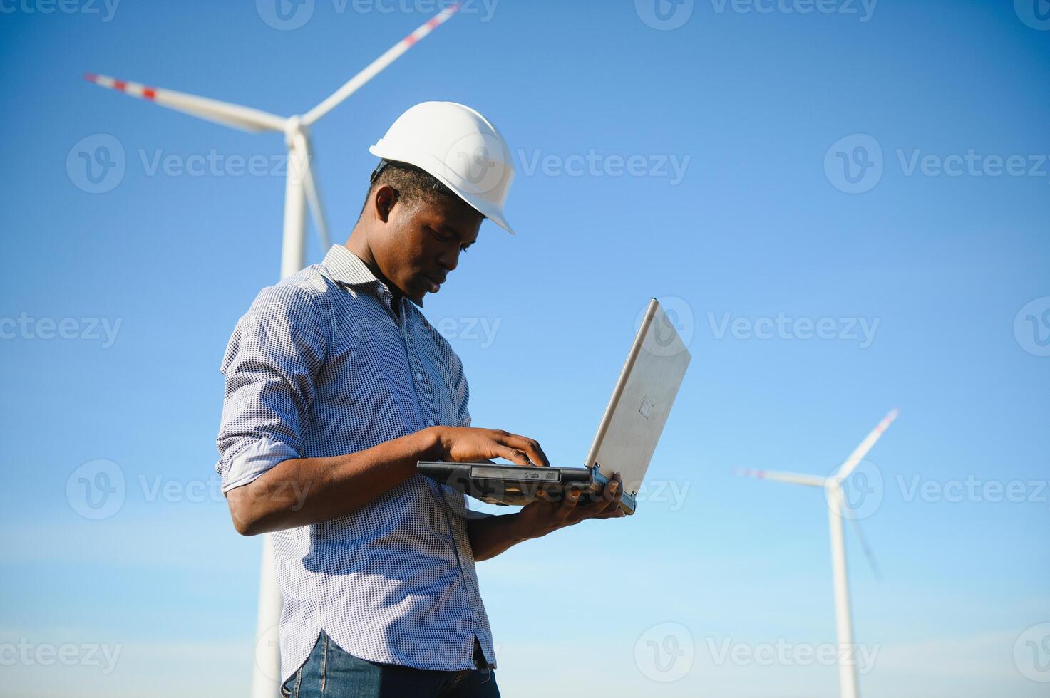 African Engineer standing and hoding laptop with wind turbine photo