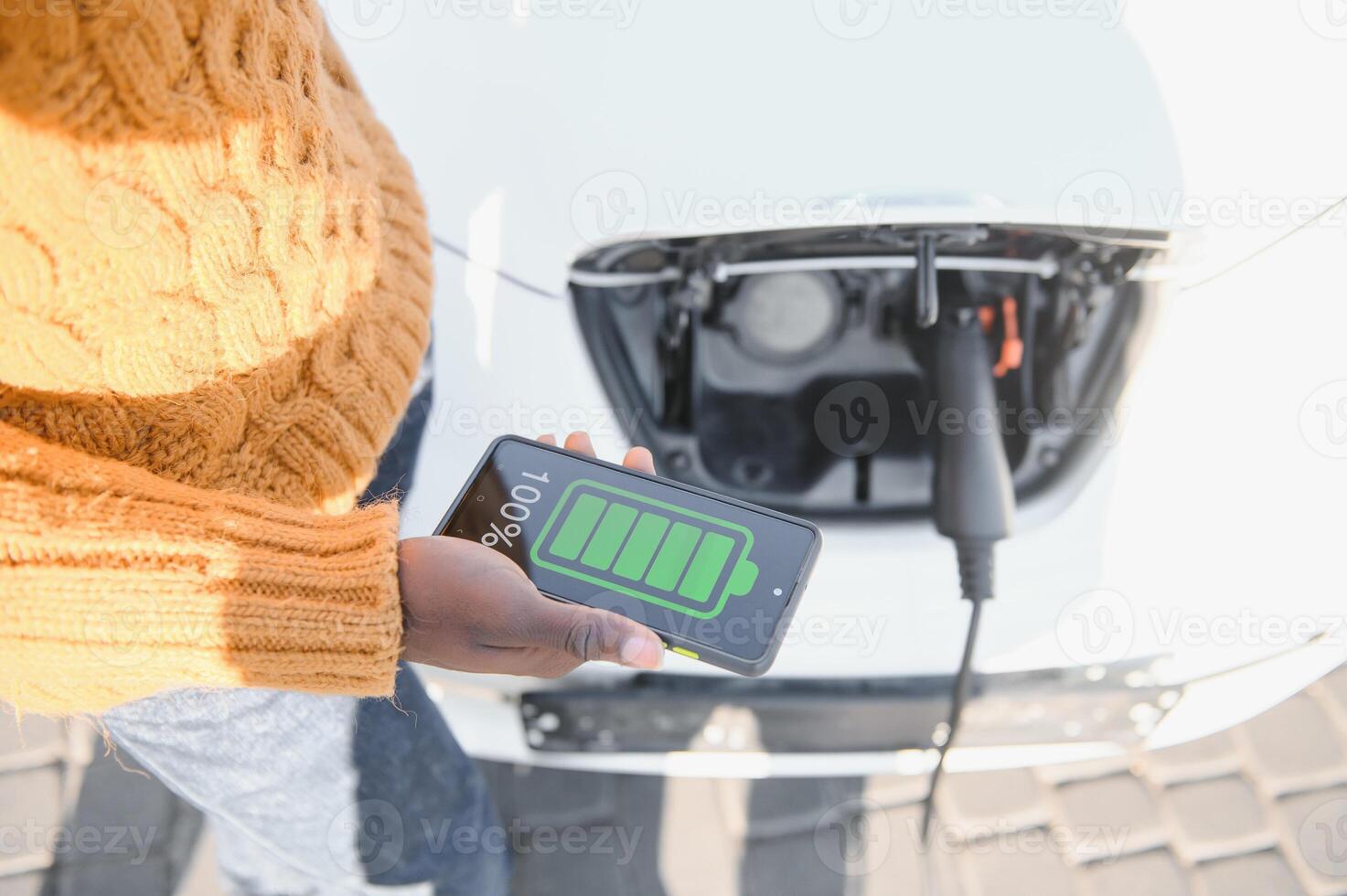 Smartphone app shows charging status of the electric car battery. Electro transport concept photo