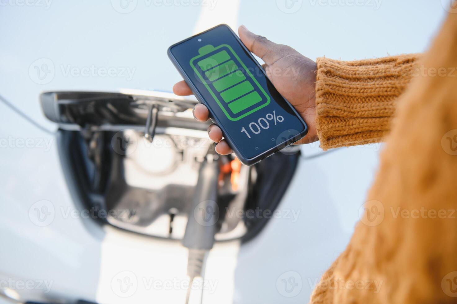 Smartphone app shows charging status of the electric car battery. Electro transport concept photo