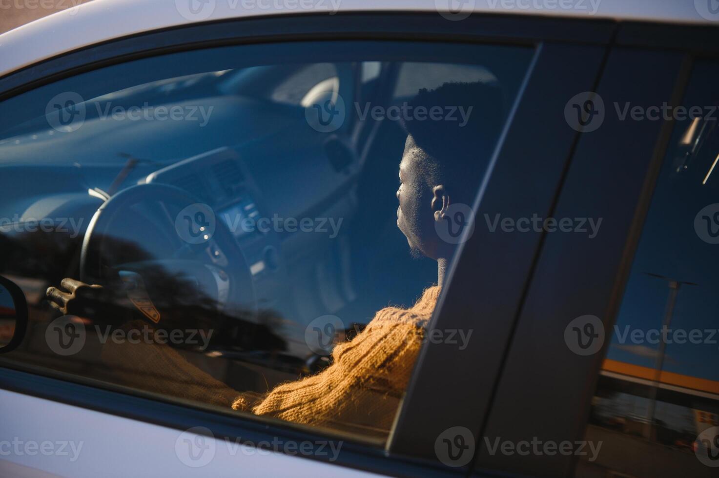 Handsome young African American man in his new high-tech electric vehicle while drinking. Self driving vehicle concept photo