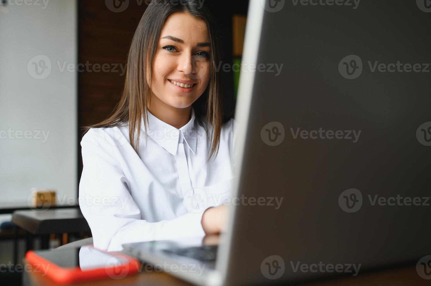 Young woman successful manager is talking via mobile phone with possible financial company employee and reading their resume on portable laptop computer during remote interview in co-working space photo