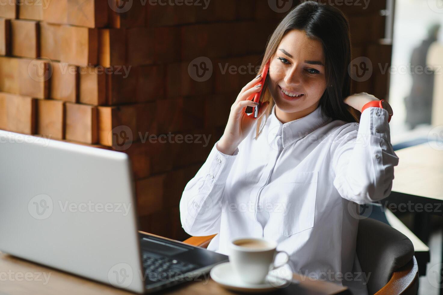 Young woman successful manager is talking via mobile phone with possible financial company employee and reading their resume on portable laptop computer during remote interview in co-working space photo