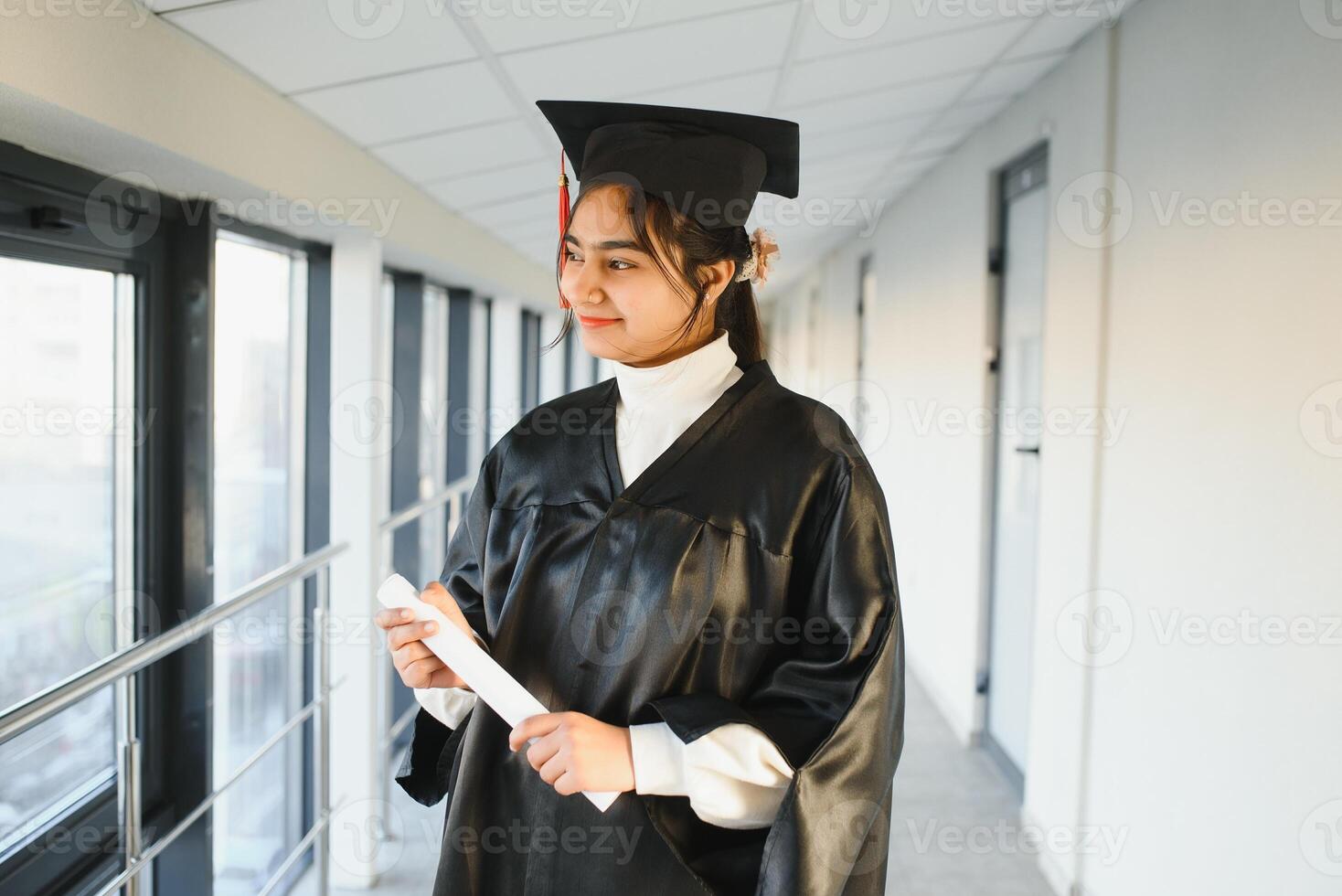 Happy Indian university student in graduation gown and cap holding diploma certificate. photo