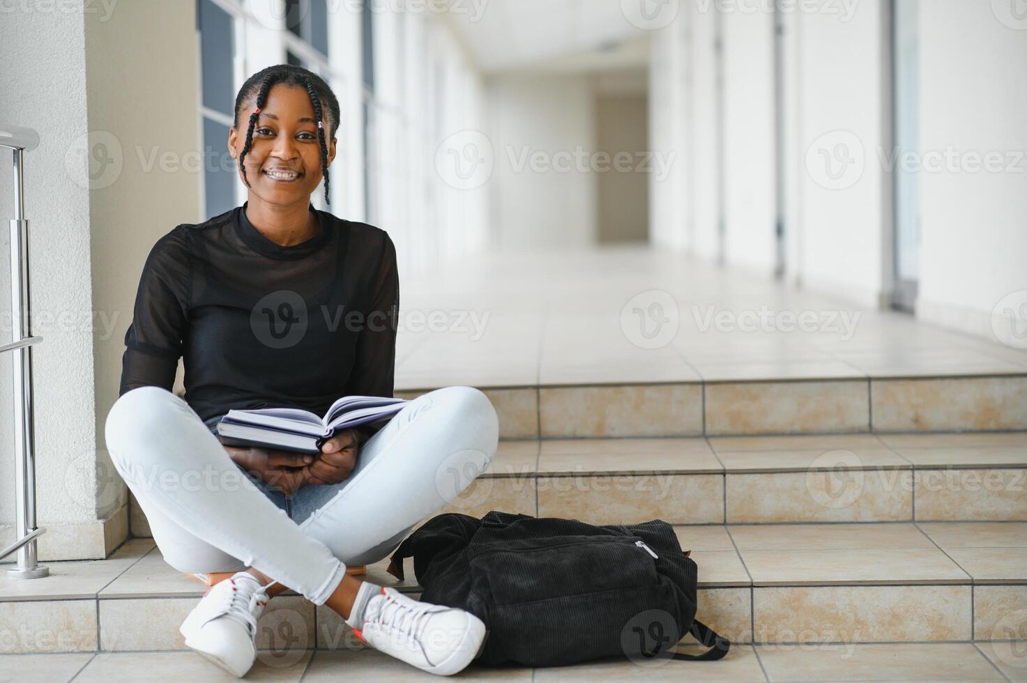 Happy smiling african-american student girl with backpack at university background. Technology, education, leisure concept photo