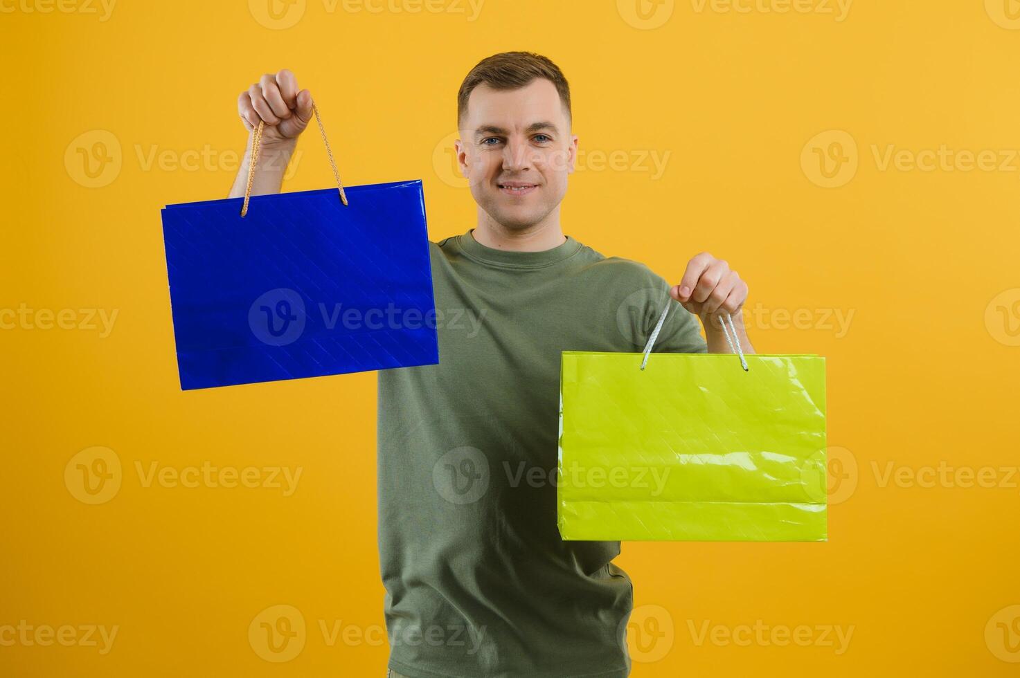 portrait of smiling couple holding shopping bags isolated on yellow background. photo