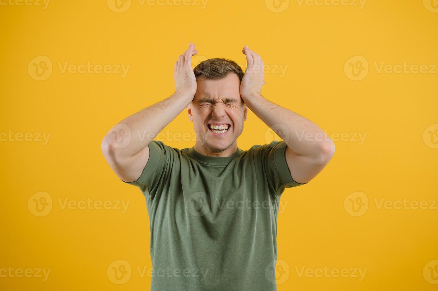 Portrait of a young man holding his head with his hands. Concept of despair and hopelessness. Frustration. Migraine photo
