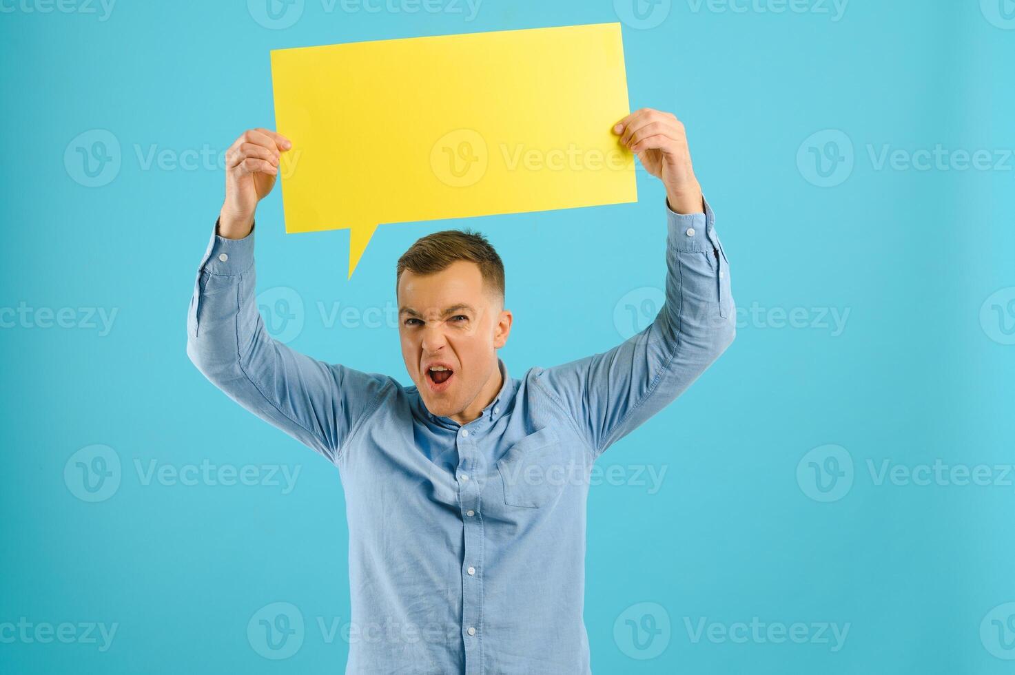 Happy smiling man holding yellow bubble speech, looking at camera over red background photo