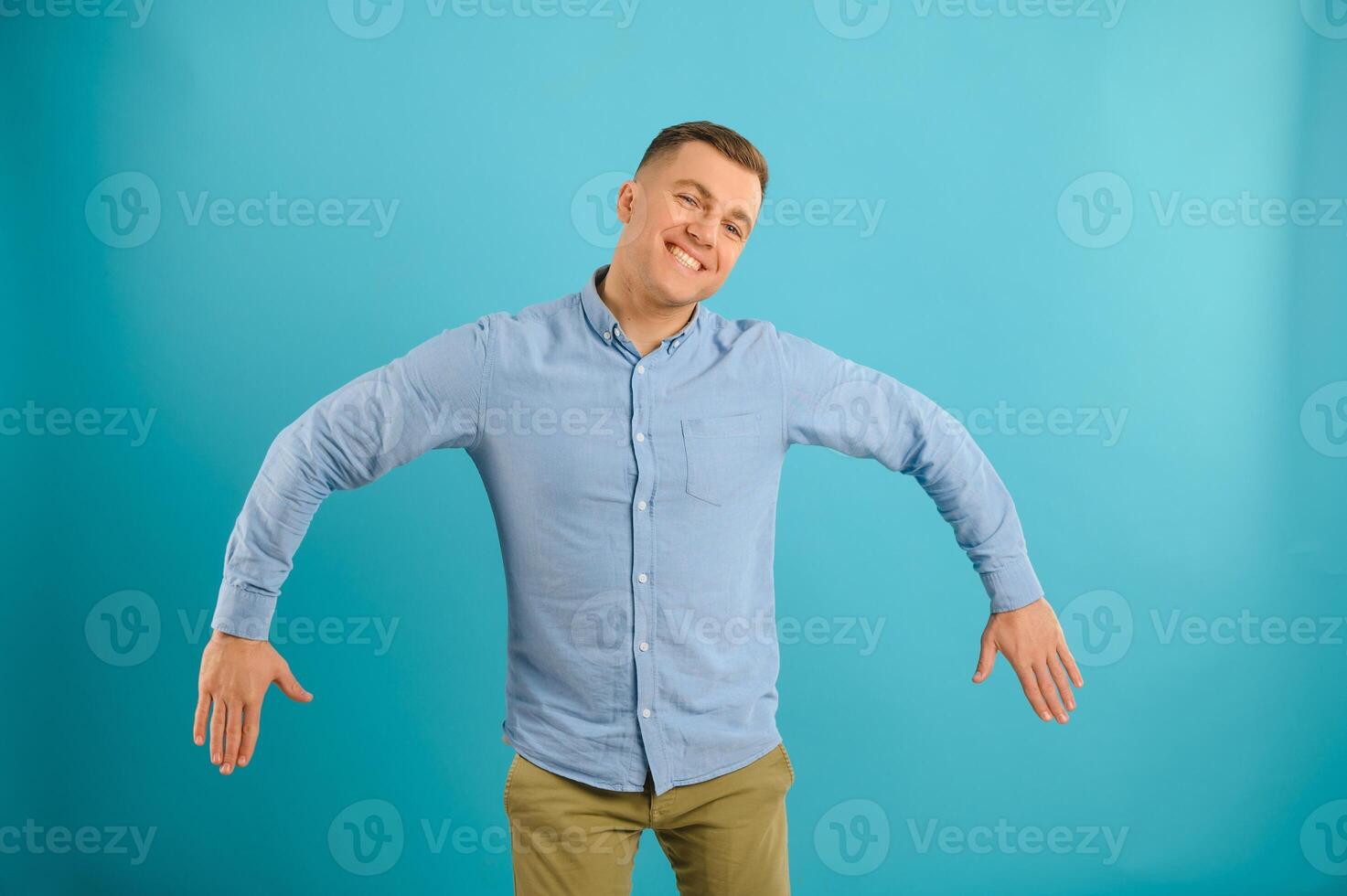 Happy smiling handsome man in clothing, showing copy space, visual imaginary or something, or pressing virtual button, aqua marine blue color background. photo