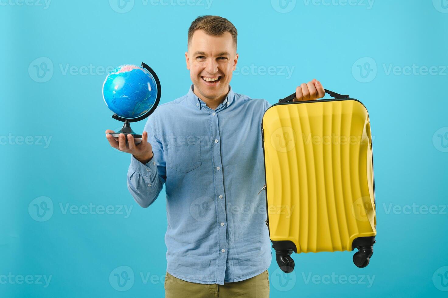 Excited traveler tourist man isolated on blue background. Passenger traveling abroad on weekends. Air flight journey concept. Holding world globe. photo