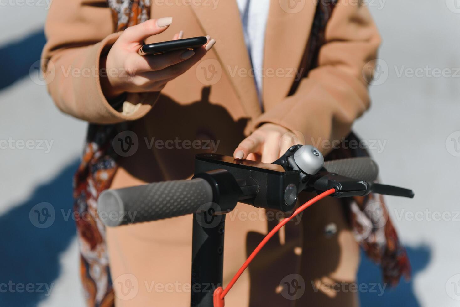 a young woman unlocks an e-scooter with her mobile phone photo