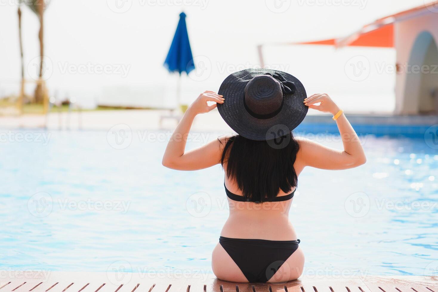 Young woman traveler relaxing and enjoying by a tropical resort pool while traveling for summer vacation, Travel concept photo