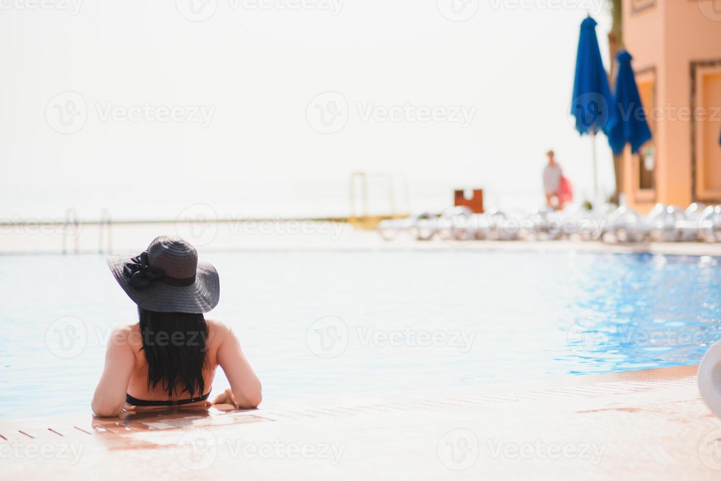 Young woman traveler relaxing and enjoying by a tropical resort pool while traveling for summer vacation, Travel concept photo