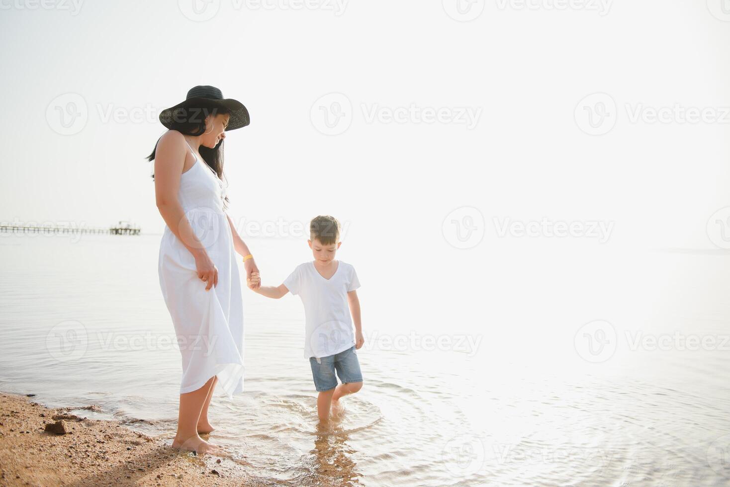 Mother and son playing on the beach at the day time. Concept of friendly family. photo