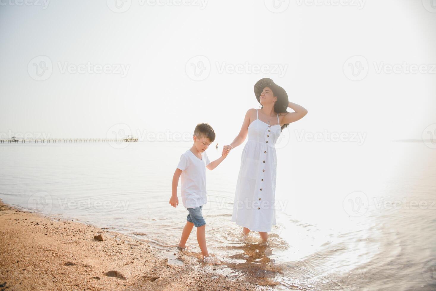 Mother and son playing on the beach at the day time. Concept of friendly family. photo