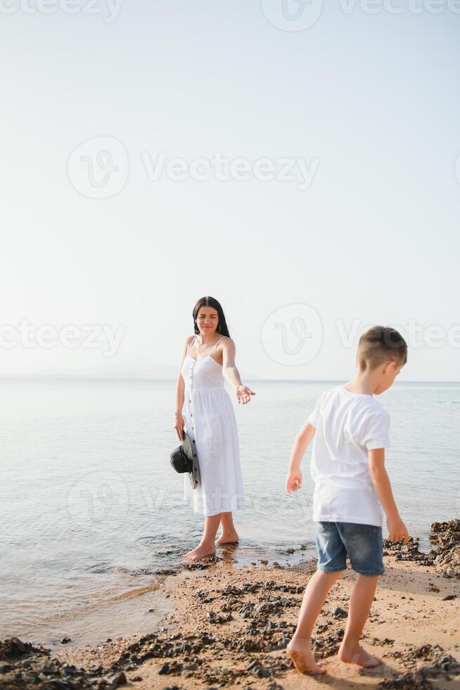 Happy mother and son walk along the ocean beach having great family time on vacation on Pandawa Beach, Bali. Paradise, travel, vacation concept photo